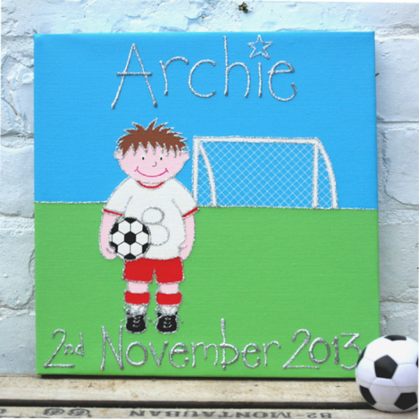 A personalised canvas picture of a little footballer in a white and red strip holding a football on a field in front of a goal.