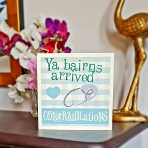 Geordie New Baby Boy card. A blue and white checked card with a blue heart and a blue safety pin. Ya bairns arrived congratulations