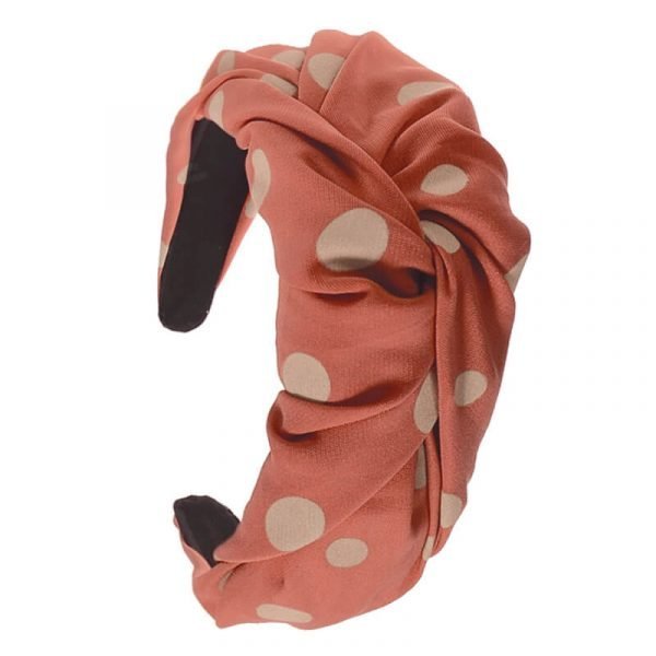 A wide Alice band for your hair with a twist in the fabric at the top; covered with a big polka dot fabric in coral pink with buff coloured dots.