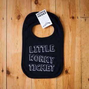 A black bib with poppers to secure around babys next with geordie phrase little worky ticket written on the front of it.