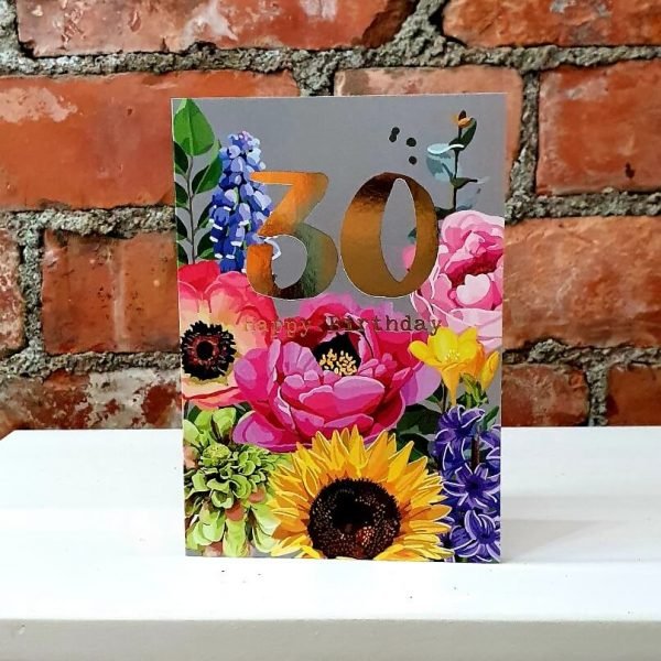 A 30th birthday card with brightly coloured watercolour flowers a grey background and 30 in vibrant gold foil