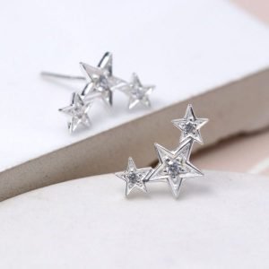 A pair of silver stud earrings which have a large star in the centre of it with a slightly smaller star either side of it. All of the stars have little crystals insiide of them.