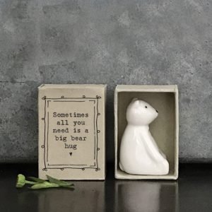 A sweet little porcelain bear keepsake kept in a little cardboard matchbox with the wording 'SOmetimes all you needs is a big bear hug' printed on it.