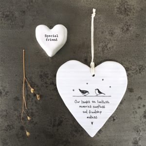 A white ceramic wobbly hanging heart from British design company East of India, with the words ' Our Laughs are Limitless, memories are countless and friendship endless.' imprinted on it.