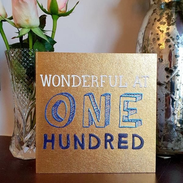 A metallic gold card with blue and white print with wonderful one hundred.