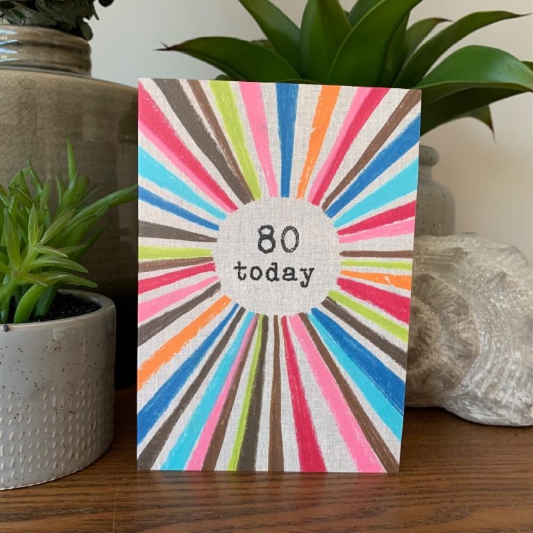 A multi coloured rainbow card with the words 80 Today printed in the centre of it.