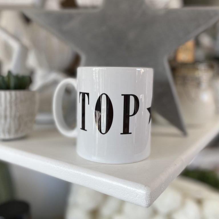 A white mug with monochrome typography print on it which says Top Dad printed around the mug.