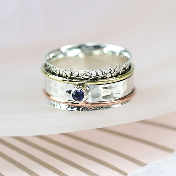 An exquisite sterling silver spinning ring with mixed metal bands and a precious blue iolite gemstone.