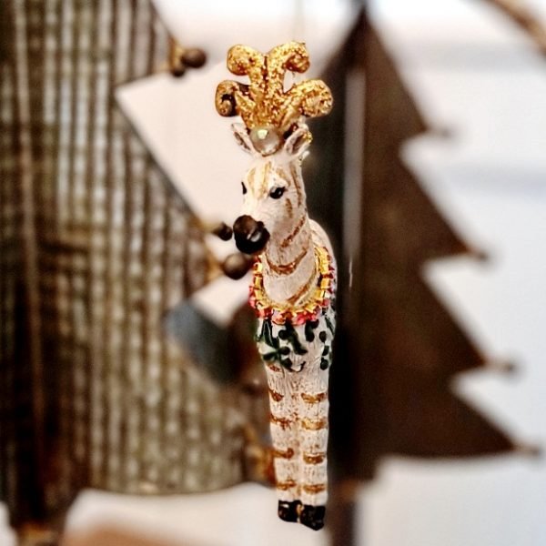 An embellished Zebra decoration with a feather crown and a garland of crystals. The resin zebra decoration has gold glitter stripes and can either hang from the tree or stand