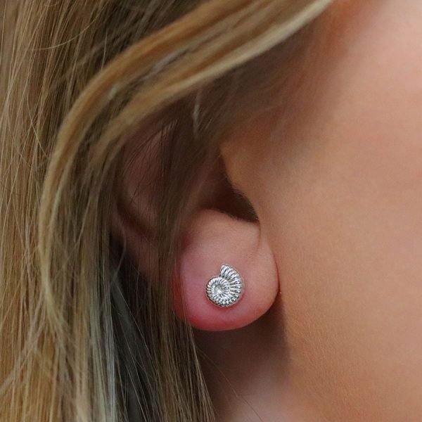 A pair of sterling silver stud earrings that are shaped like a fossil shell.