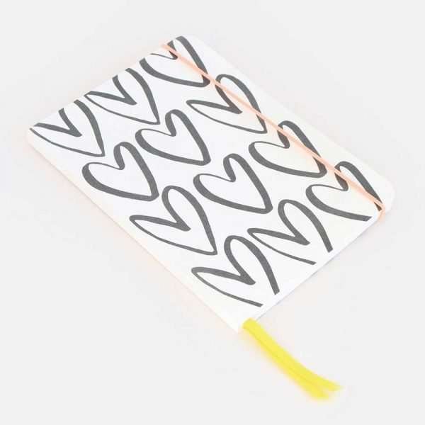 Outline Heart Notebook. An A5 notebook with ruled pages. The cover is a black and white outline heart design. A pink elastic close and yellow ribbon page marker