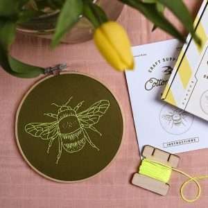 A brilliant embroidery kit with a khaki coloured material, with a pattern of a bumble bee. The kit has a circular wooden embroidery hoop. The thread is yellow which makes the design stand out on this lovely wall hanging.