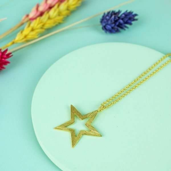 A short gold necklace with a brushed open star pendant