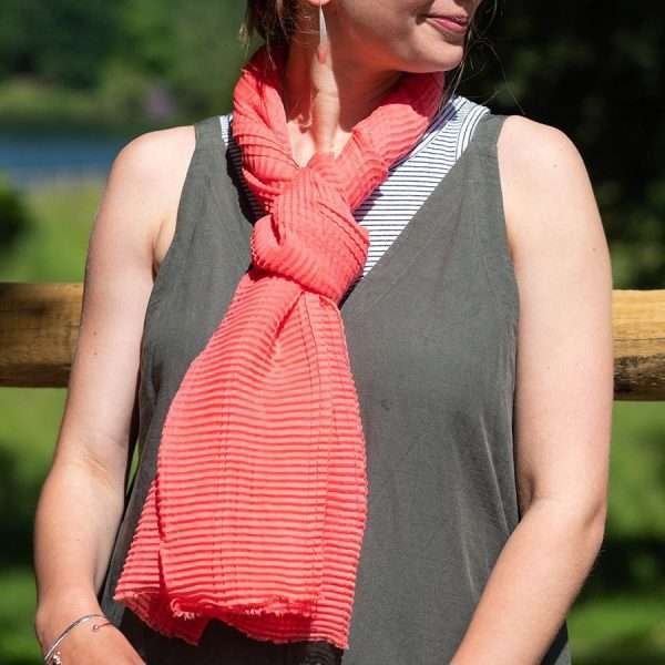 Coral Lightweight Crinkle Scarf. Lightweight scarf in coral pink with a fine pleated texture and lightly frayed ends.