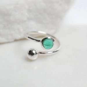 A sterling Silver open adjustable ring with a ball on one end and an emerald May birthstone set at the other.