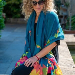 Teal blue scarf made from Repreve, a yarn created from recycled plastic bottles, featuring a vibrant tropical paradise print edge