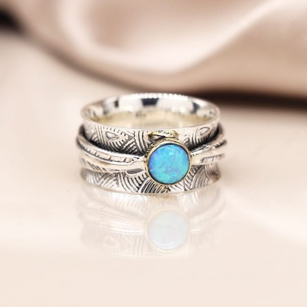 Sterling silver spinning ring with deco embossed detail and a single opal cabochon on a moving leaf band