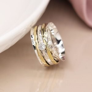 Sterling silver spinning ring with hammered surface and triple moving bands, one silver with a cut gemstone and two brass